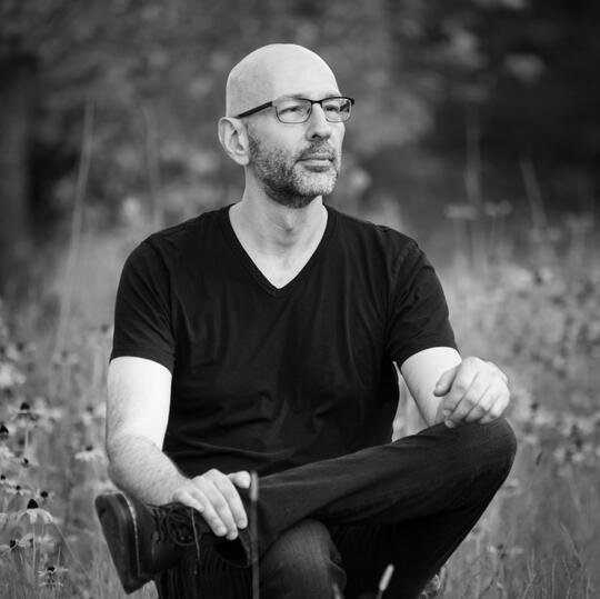 Grant Williams, seated in a field of wildflowers, looking into the distance.